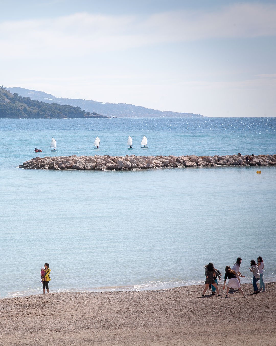 Persone riprese in lontananza su una spiaggia deserta.