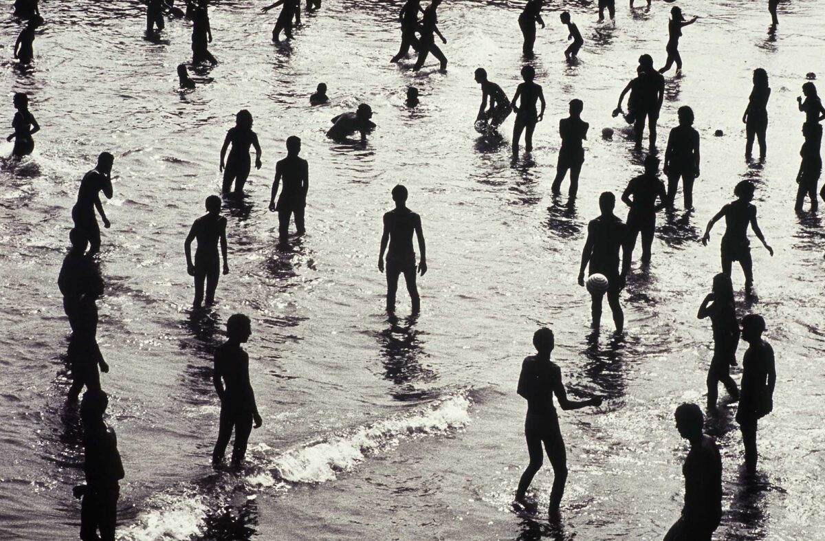 Silhouettes di ragazzi che giocano nell'acqua di una spiaggia, fotografia in bianco e nero.